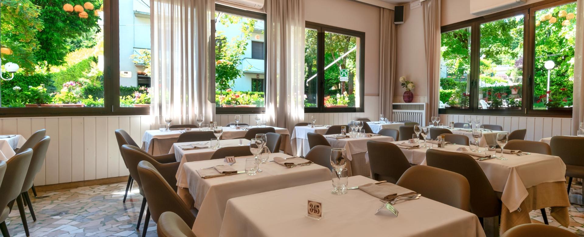 Ristorante luminoso con finestre grandi e tavoli apparecchiati elegantemente.