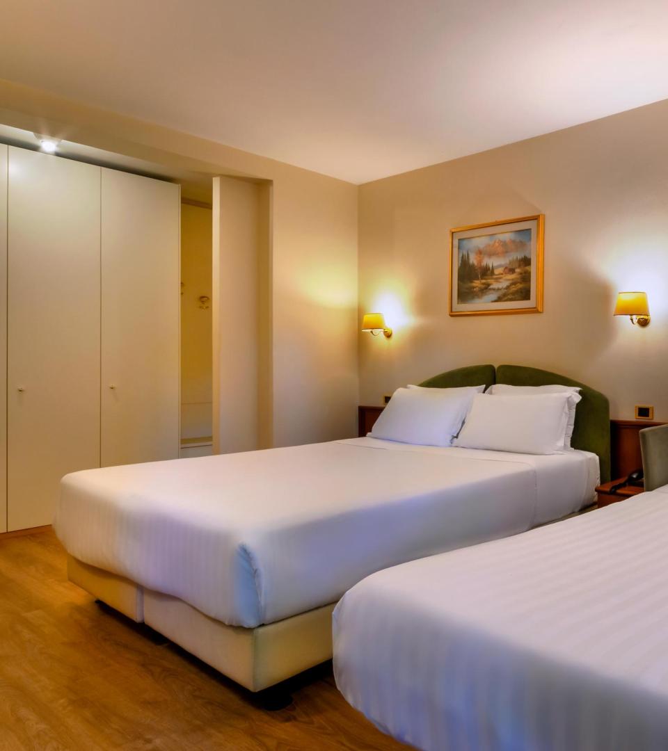Camera d'albergo con due letti matrimoniali e arredamento accogliente.